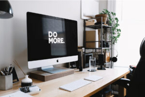 A minimalistic workspace with a computer, water and other working tools representing productivity and focus.