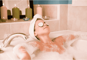 Woman relaxing in a bathtub with cucumber slices on her eyes to reduce dark circles.