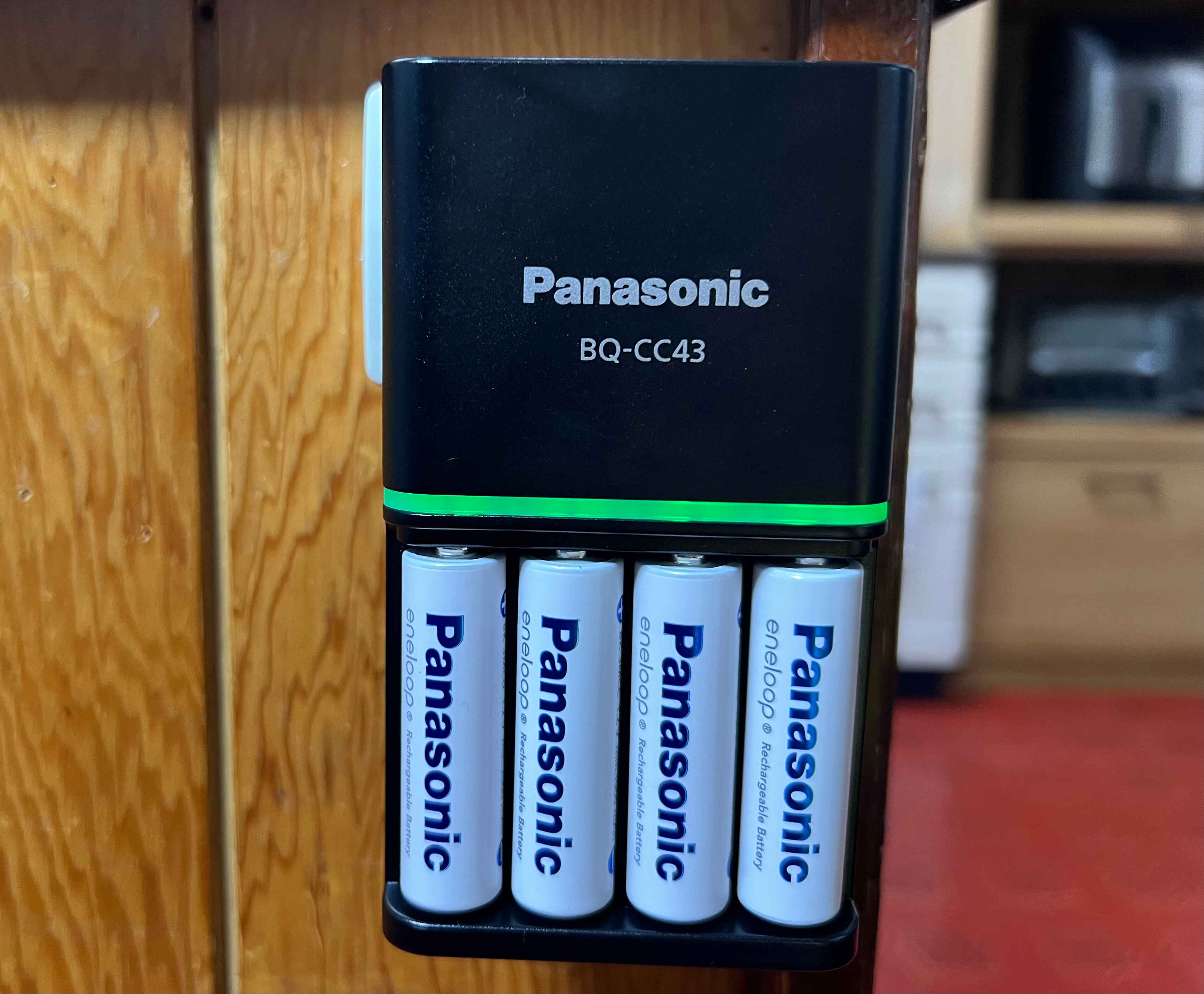 Panasonic Eneloop charger showing green charging light.